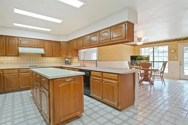 a kitchen with stainless steel appliances granite countertop a stove top oven a sink a dining table and chairs