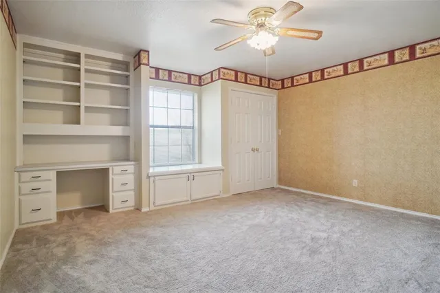 a view of an empty room with a fireplace and a ceiling fan