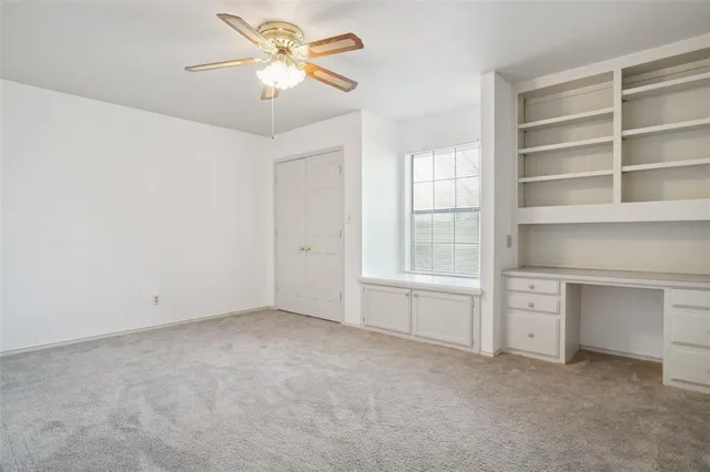 a view of an empty room with a window and a ceiling fan