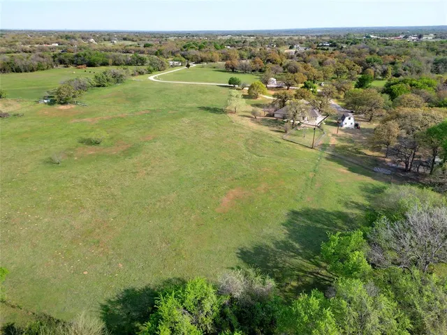 an aerial view of residential houses with outdoor space and trees