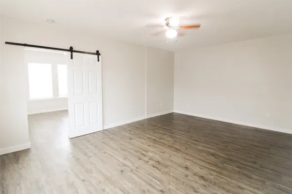a view of empty room with wooden floor and fan