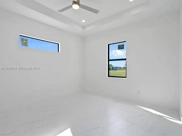 an empty room with windows and fan