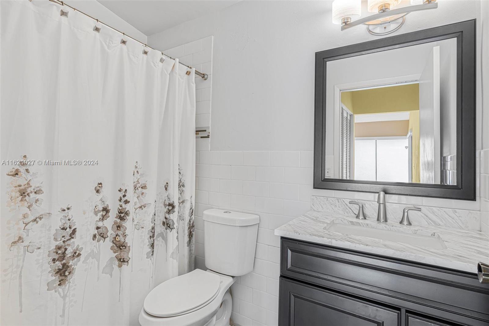 6604 Southwest 152nd Place, Unit 2604 Miami, FL 33193 - Photo 16 of 27 a bathroom with a granite countertop sink toilet and mirror