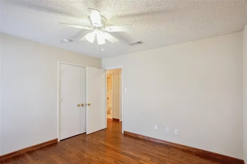 an empty room with wooden floor and fan