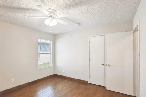 an empty room with wooden floor closet and windows