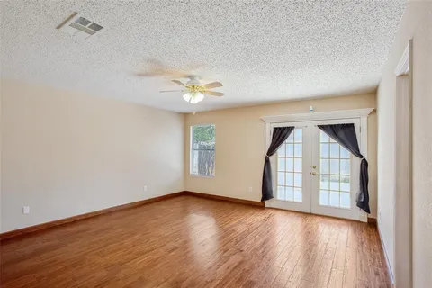 a view of an empty room with wooden floor and a window