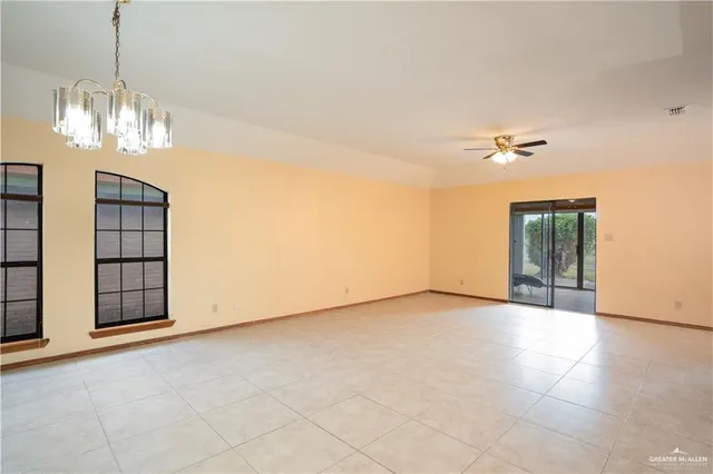 a view of an empty room with chandelier fan
