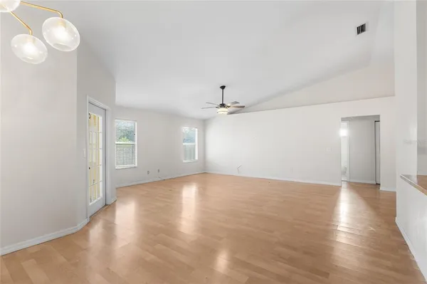a view of an empty room with window and wooden floor
