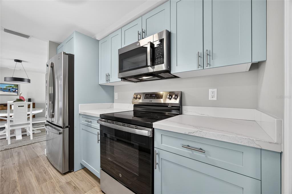 6035 Manasota Key Road Englewood, FL 34223 - Photo 17 of 54 a kitchen with stainless steel appliances white cabinets and a stove a oven with wooden floor
