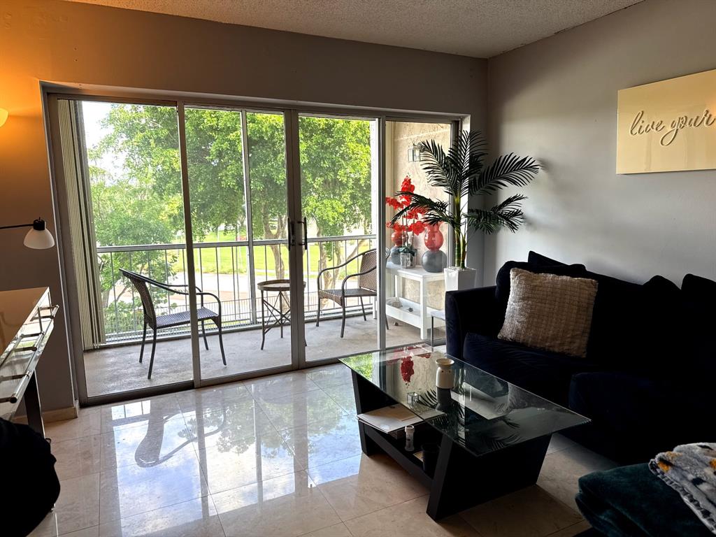 505 Spencer Drive, Unit 210 West Palm Beach, FL 33409 - Photo 7 of 12 a living room with furniture and a floor to ceiling window