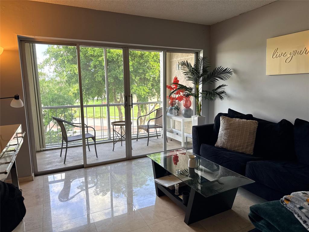 505 Spencer Drive, Unit 210 West Palm Beach, FL 33409 - Photo 8 of 12 a living room with furniture and a floor to ceiling window