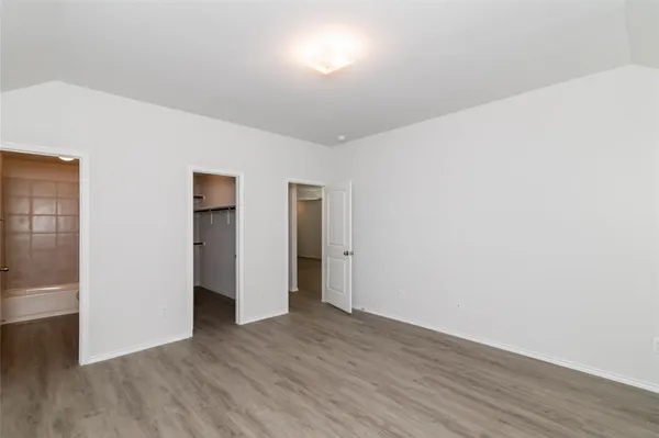 a view of an empty room with wooden floor and closet