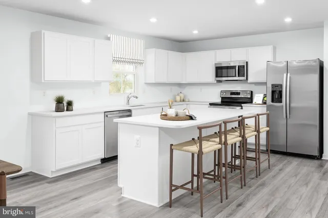 a kitchen with a sink a microwave a refrigerator and white cabinets