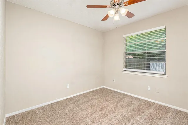 an empty room with a window and a fan