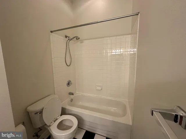 a bathroom with a granite countertop bathtub shower sink vanity and toilet