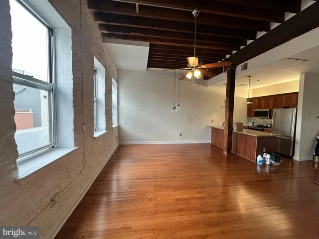 a view of a room with kitchen island stainless steel appliances wooden floor and window