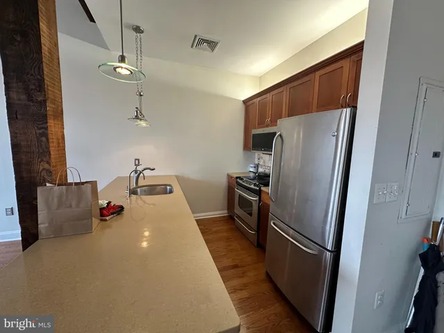 a storage room with stainless steel appliances wooden floor and chandelier