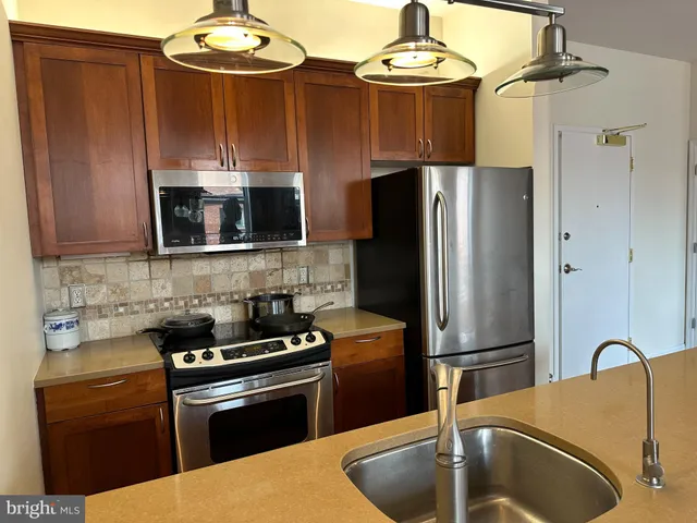 a kitchen with stainless steel appliances granite countertop a refrigerator a stove and a sink