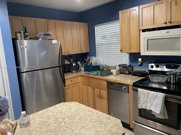 a kitchen with stainless steel appliances granite countertop a refrigerator a sink dishwasher a stove with wooden cabinets