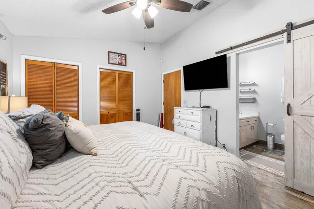 a large bedroom with a bed and a flat tv screen on the dresser