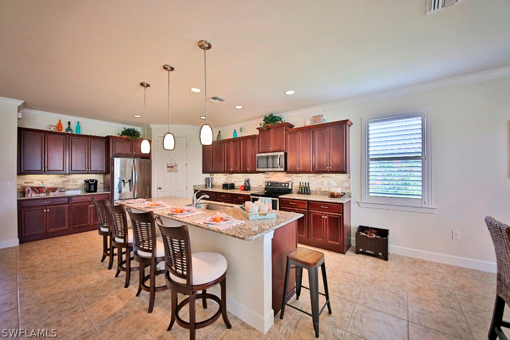 10871 Rutherford Road Fort Myers, FL 33913 - Photo 4 of 25 a kitchen with stainless steel appliances a stove a refrigerator a sink a dining table and chairs
