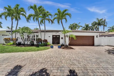 a front view of a house with garden and a pond