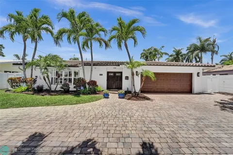 a front view of a house with garden and a pond