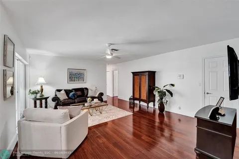 a living room with furniture kitchen view and a wooden floor