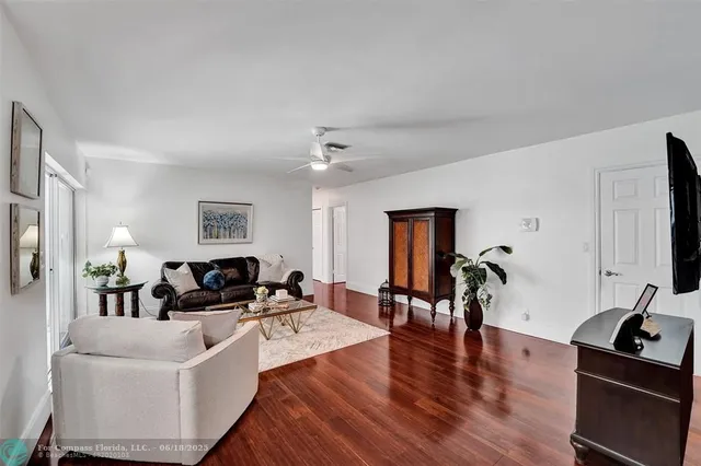 a living room with furniture kitchen view and a wooden floor