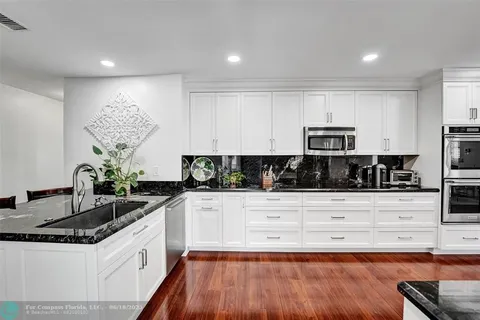 a kitchen with stainless steel appliances granite countertop a sink and white cabinets