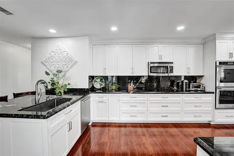 a kitchen with stainless steel appliances granite countertop a sink and white cabinets