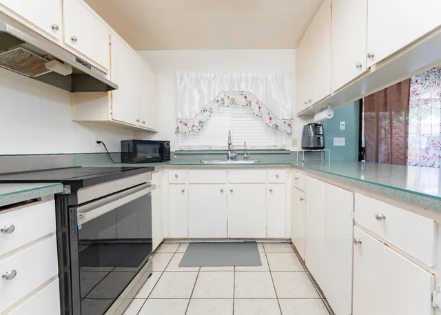 a kitchen with granite countertop white cabinets and white appliances