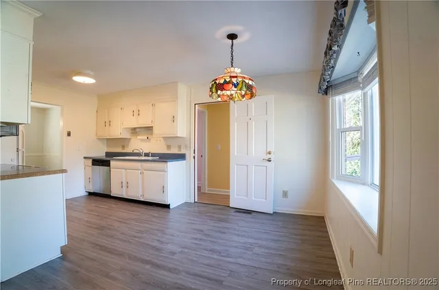 a kitchen with granite countertop white cabinets white appliances and a sink