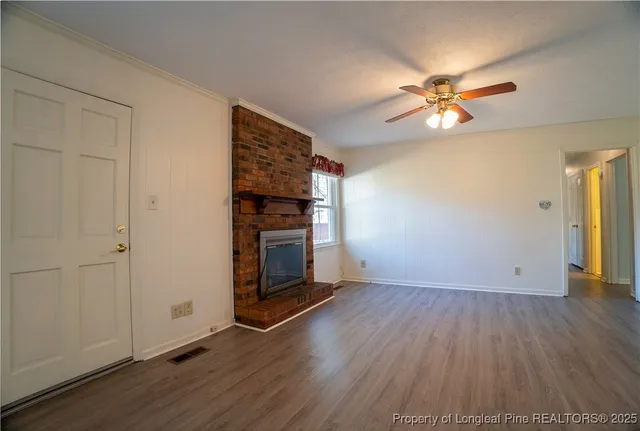 an empty room with wooden floor chandelier fan and windows