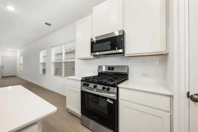 a kitchen with stainless steel appliances white cabinets and a stove top oven
