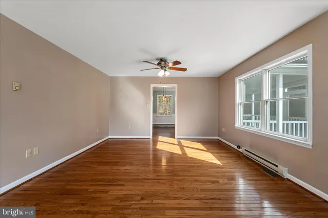 a view of an empty room with wooden floor and a window
