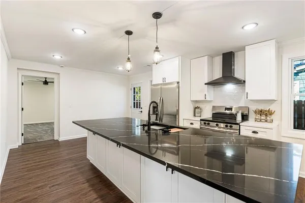 a kitchen with stainless steel appliances granite countertop a sink a stove and a wooden floors