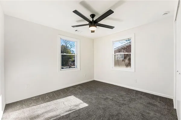 an empty room with ceiling fan and windows