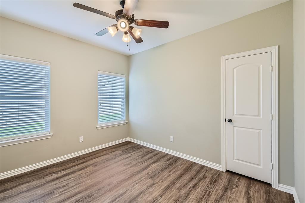 204 West Patton Street Alvarado, TX 76009 - Photo 12 of 17 an empty room with wooden floor chandelier fan and windows
