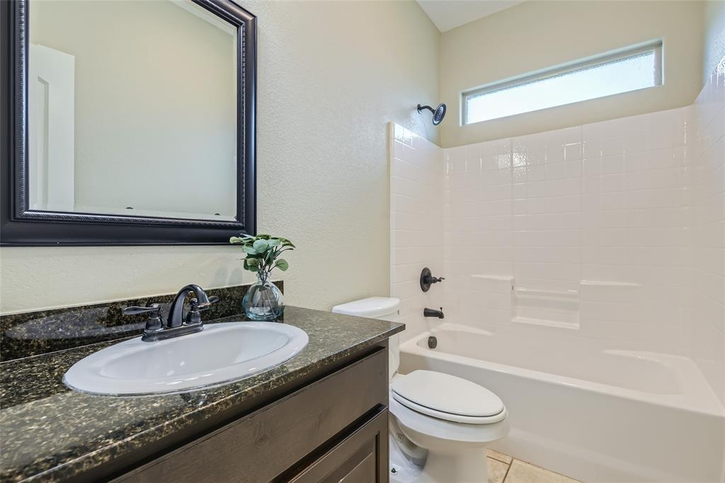 204 West Patton Street Alvarado, TX 76009 - Photo 13 of 17 a bathroom with a granite countertop sink toilet and a mirror