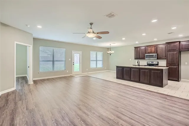 a large kitchen with stainless steel appliances kitchen island a large counter top a sink and a chandelier