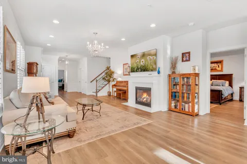 a dining room with wooden floor a chandelier a glass table and chairs