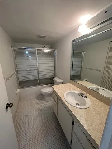 a bathroom with a granite countertop sink a toilet a mirror and shower