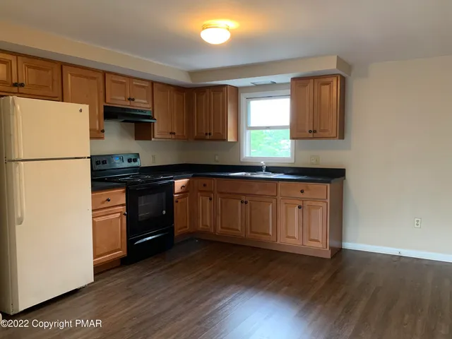 a kitchen with kitchen island granite countertop a sink cabinets and stainless steel appliances