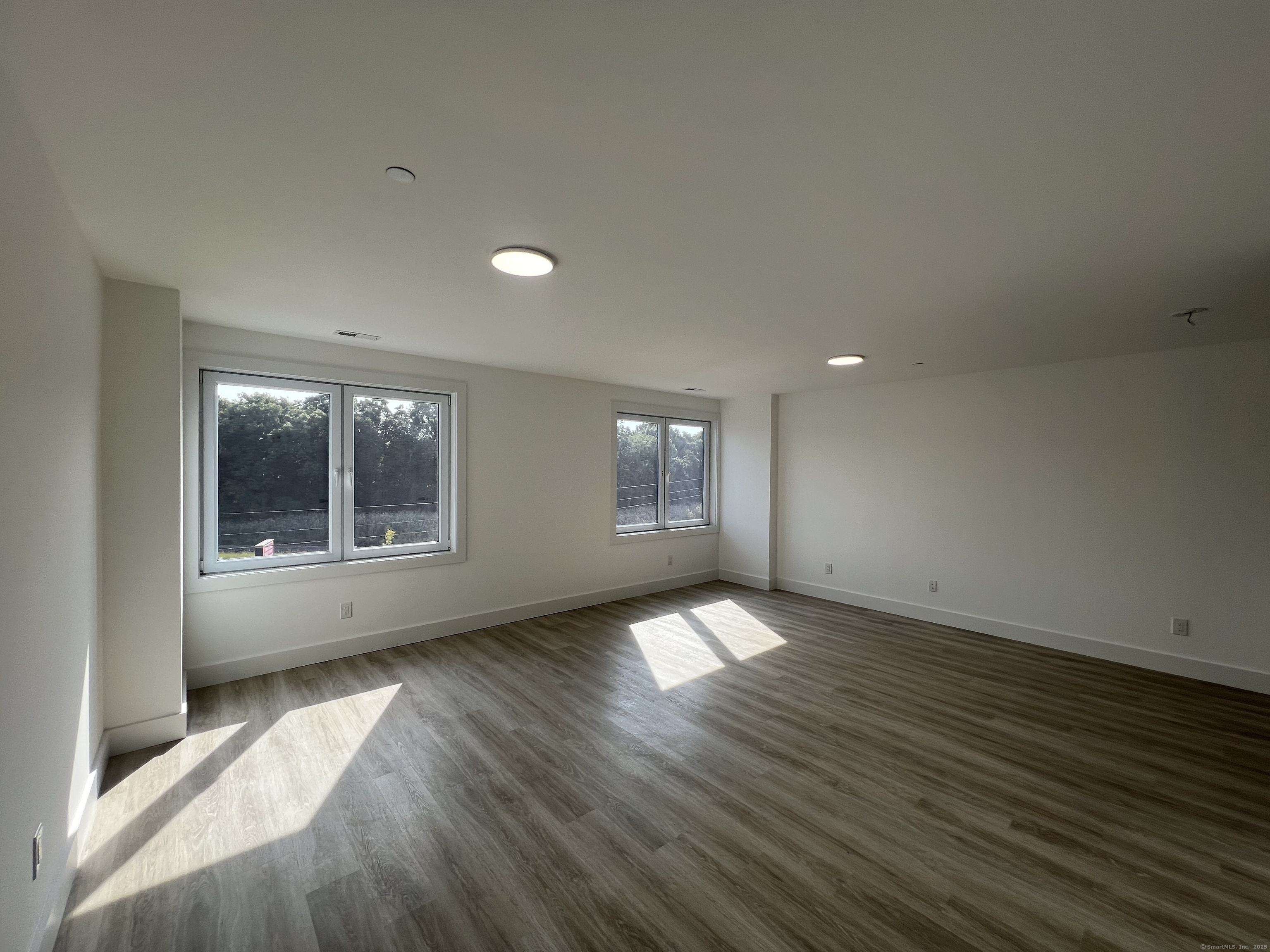 211 Ferry Boulevard, Unit 203 Stratford, CT 06615 - Photo 7 of 16 an empty room with wooden floor and windows