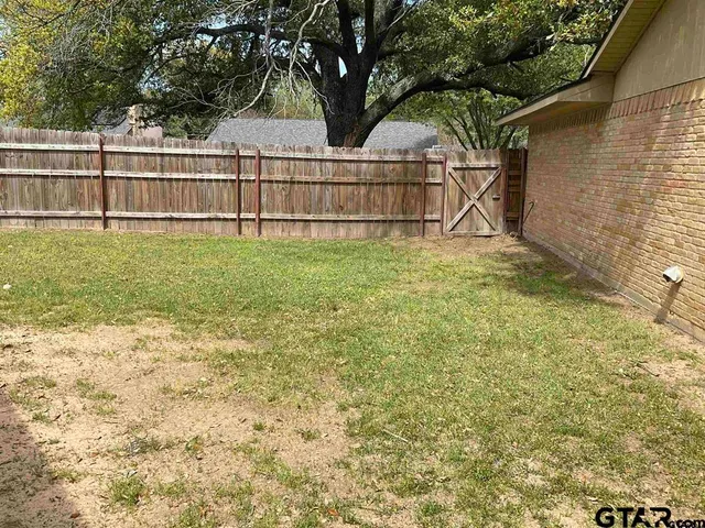 a view of backyard with wooden fence