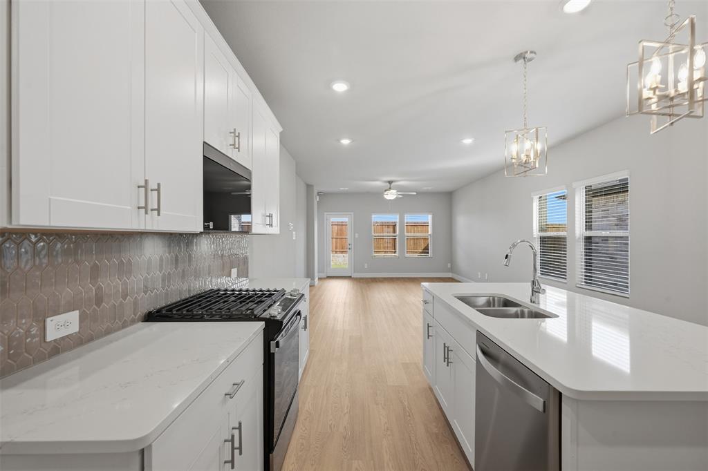 1701 Arches Road Anna, TX 75409 - Photo 5 of 19 Kitchen featuring white cabinetry, light-toned wood-finish flooring, a stainless-steel sink, an integrated dishwasher, and pendant lighting fixtures