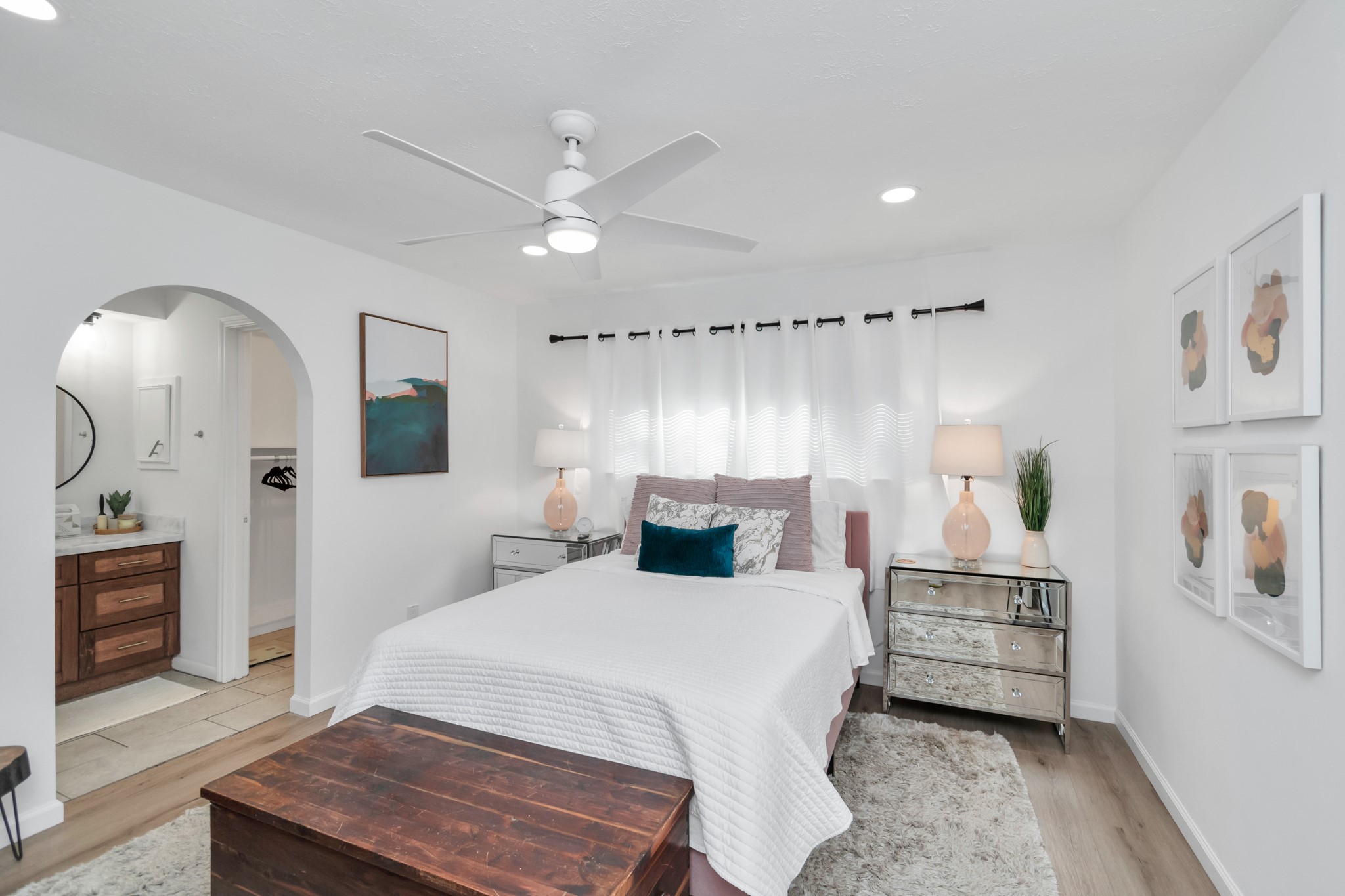 2718 Lazy Spring Drive Houston, TX 77080 - Photo 13 of 32 Spacious primary bedroom filled with natural light. Features white oak-look LVP flooring, a ceiling fan, and an arched entry leading to the vanity area.
