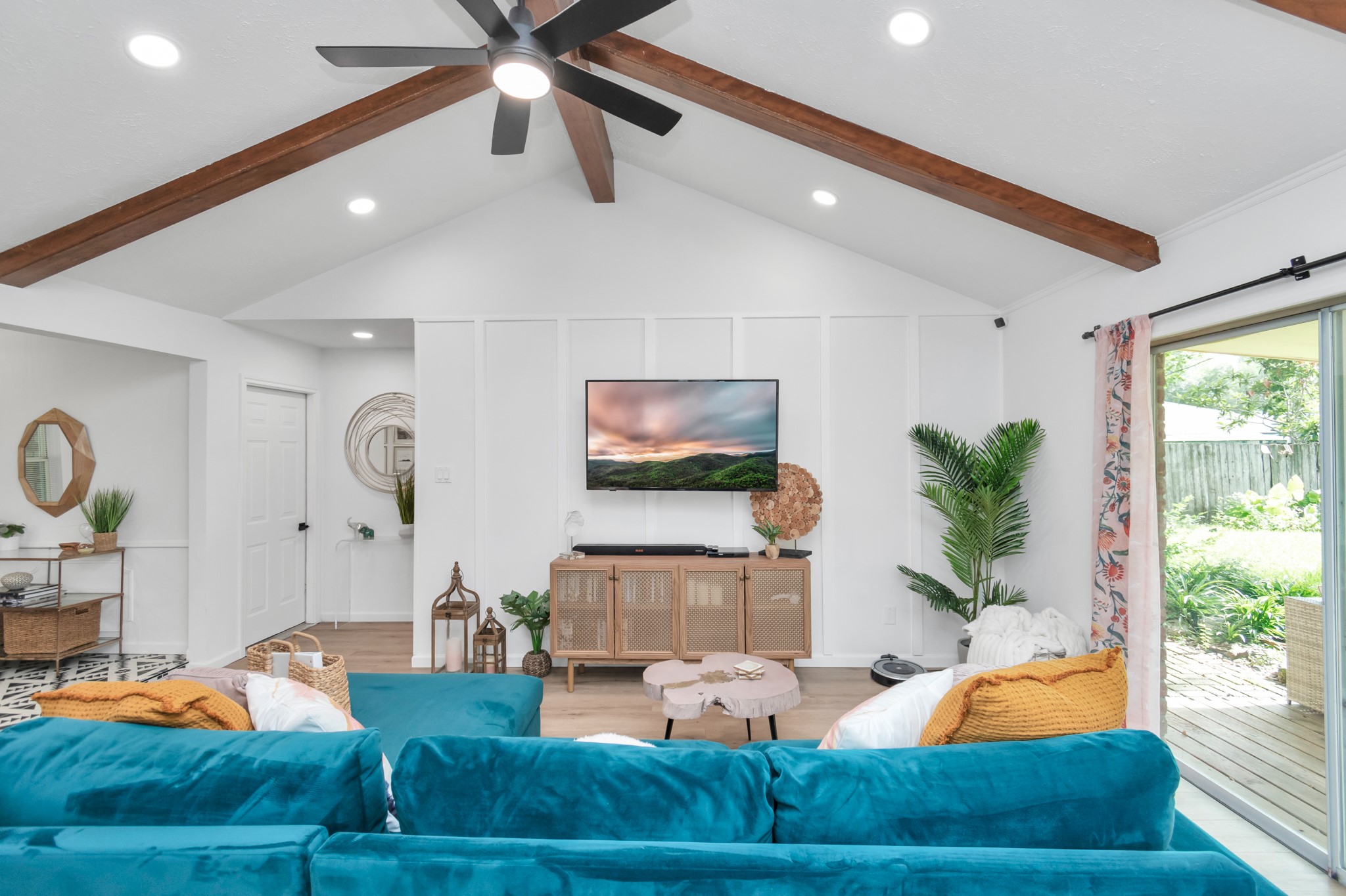2718 Lazy Spring Drive Houston, TX 77080 - Photo 9 of 32 Bright living room with vaulted ceilings and wood beams. Features a comfortable seating area, mounted TV, and stylish finishes. Sliding glass doors bring in natural light and open to the backyard.