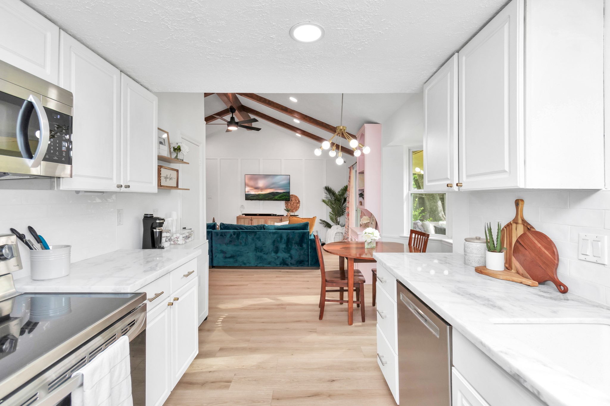 2718 Lazy Spring Drive Houston, TX 77080 - Photo 10 of 32 Modern kitchen with white cabinets and stone countertops. Opens to the living area with vaulted ceilings and wood beams.